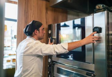 Commercial kitchen staff adjusting controls on a professional oven.