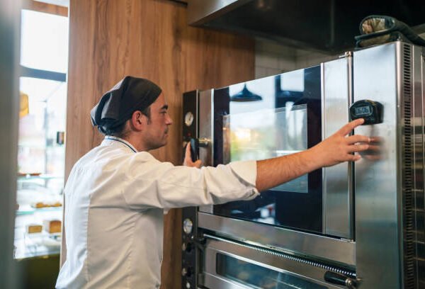 Commercial kitchen staff adjusting controls on a professional oven.