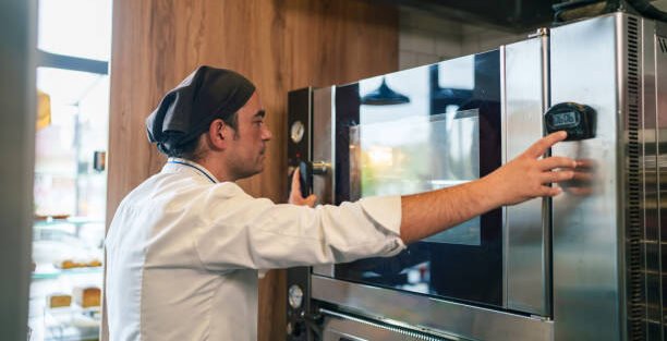 Commercial kitchen staff adjusting controls on a professional oven.